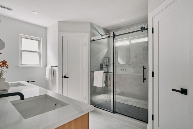 full bath with plenty of natural light, a sink, a stall shower, and double vanity