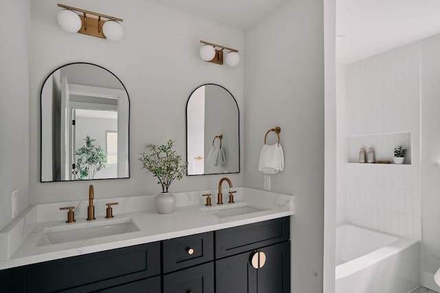 bathroom with a sink, a bathing tub, and double vanity