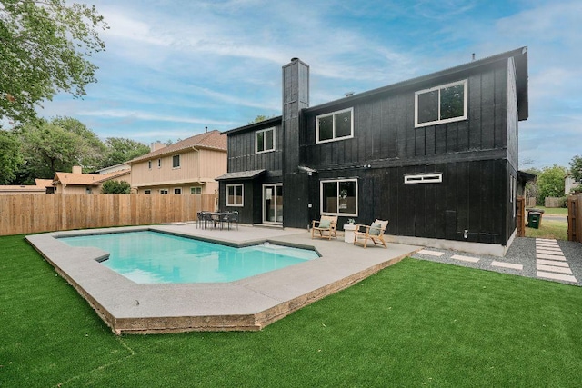 rear view of house with a lawn, fence, a chimney, and a fenced in pool