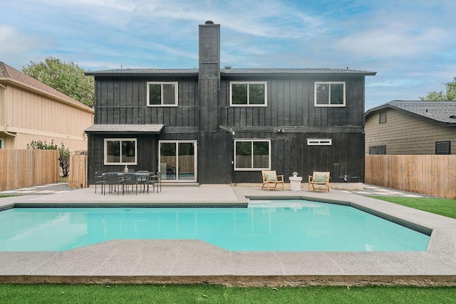 rear view of house with a fenced in pool, a fenced backyard, a chimney, and a patio