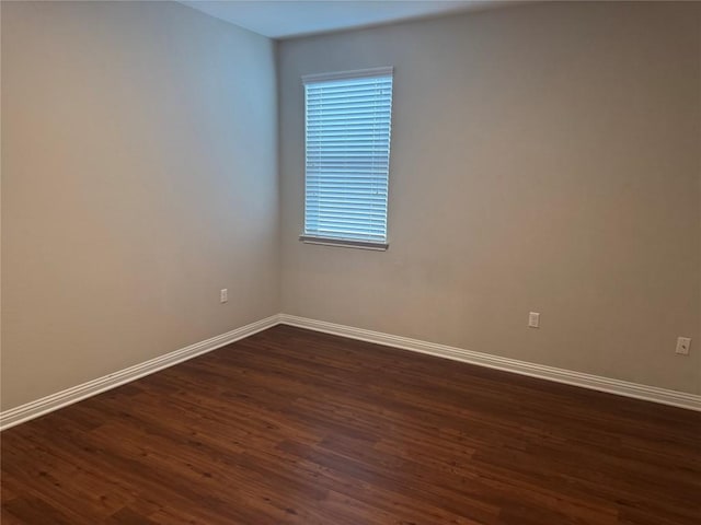 empty room with baseboards and dark wood-style flooring