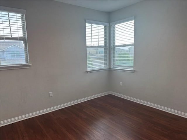 empty room featuring baseboards and dark wood finished floors