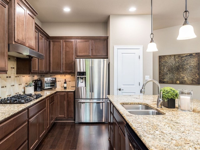 kitchen featuring appliances with stainless steel finishes, hanging light fixtures, a sink, dark wood-style floors, and under cabinet range hood
