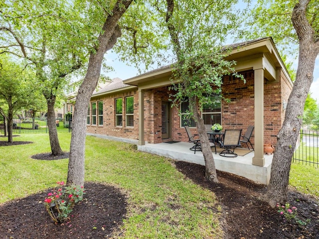 back of property with a yard, brick siding, fence, and a patio