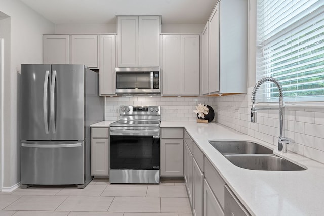 kitchen with a sink, appliances with stainless steel finishes, backsplash, and light countertops