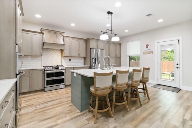 1400 Hargis Creek Trl, Austin, TX 78717 - kitchen with appliances with stainless steel finishes, tasteful backsplash, light countertops, a kitchen island with sink, and recessed lighting