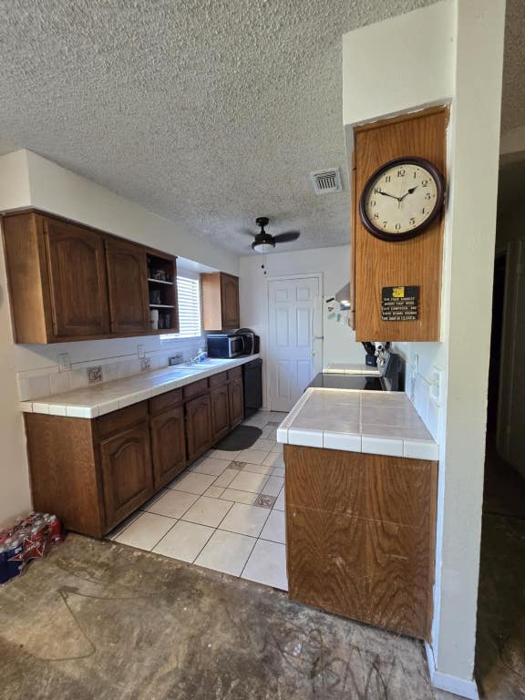 18215 Center St, Jonestown, TX 78645 - kitchen with visible vents, open shelves, a textured ceiling, and tile counters