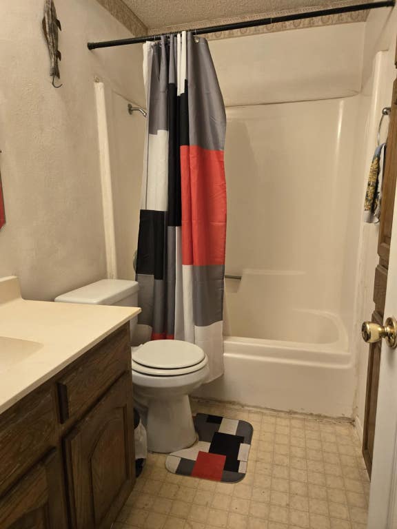 18215 Center St, Jonestown, TX 78645 - bathroom featuring toilet, tile patterned floors, shower / bathtub combination with curtain, and vanity