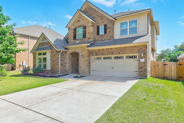 traditional-style house featuring a garage, fence, a front yard, roof with shingles, and concrete driveway