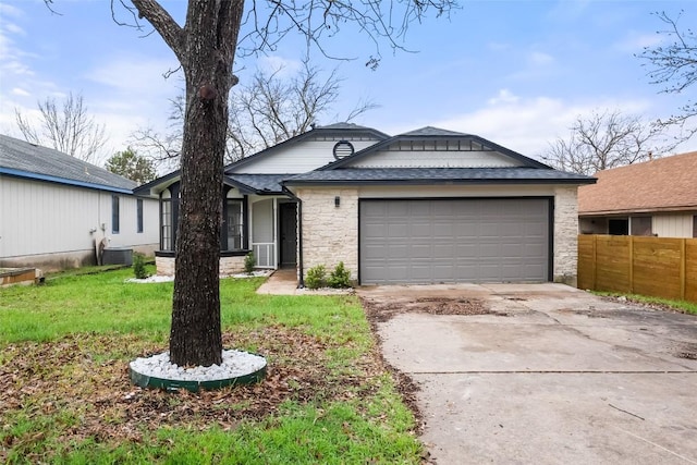 view of front facade featuring fence, stone siding, cooling unit, an attached garage, and driveway