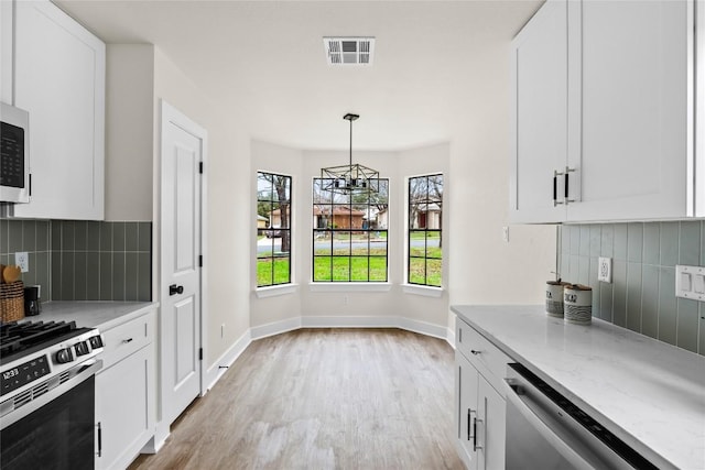 kitchen with stainless steel appliances, visible vents, decorative backsplash, and light wood-style flooring