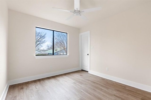 spare room with baseboards, ceiling fan, and wood finished floors