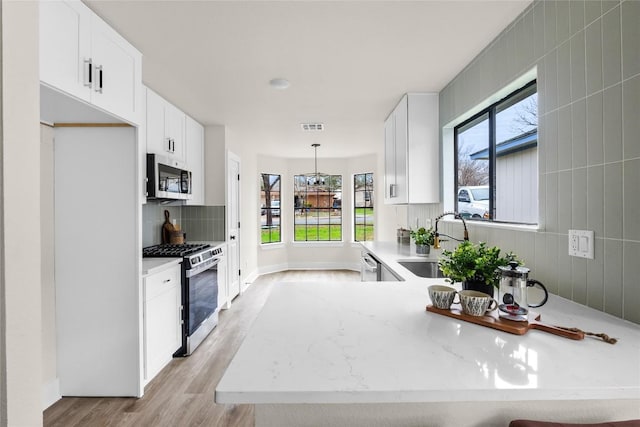 kitchen with visible vents, a sink, light wood-style flooring, appliances with stainless steel finishes, and a wealth of natural light