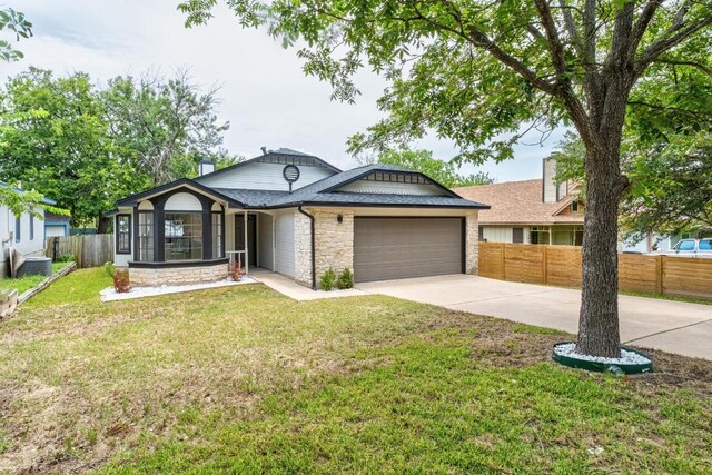 927 Peggotty Pl, Austin, TX 78753 - ranch-style home with a garage, driveway, stone siding, and roof with shingles