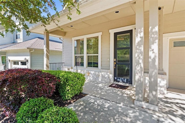 doorway to property with covered porch, roof with shingles, and stone siding