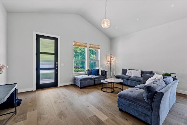 living area with baseboards, vaulted ceiling, and wood finished floors