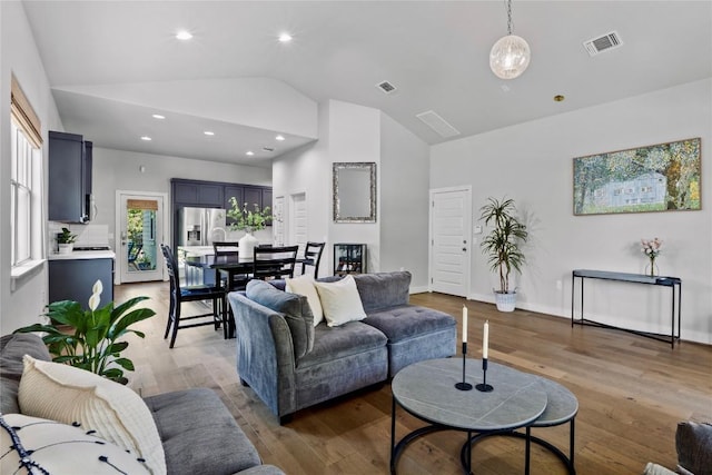 living area with visible vents, recessed lighting, light wood finished floors, and high vaulted ceiling