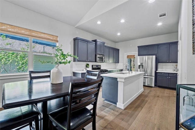 kitchen featuring light countertops, stainless steel appliances, visible vents, and tasteful backsplash