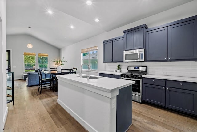 kitchen with appliances with stainless steel finishes, a sink, light countertops, light wood-style flooring, and vaulted ceiling