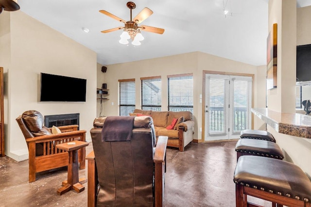 living room featuring a fireplace, a ceiling fan, baseboards, lofted ceiling, and finished concrete floors