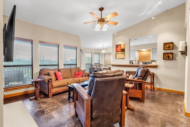 living area with baseboards, ceiling fan, finished concrete floors, and lofted ceiling