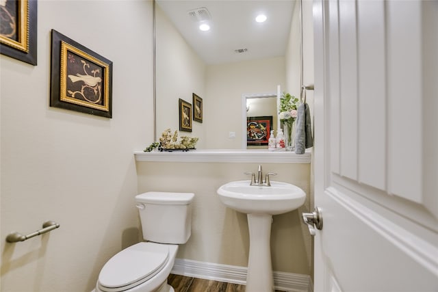 half bathroom featuring visible vents, baseboards, wood finished floors, and toilet