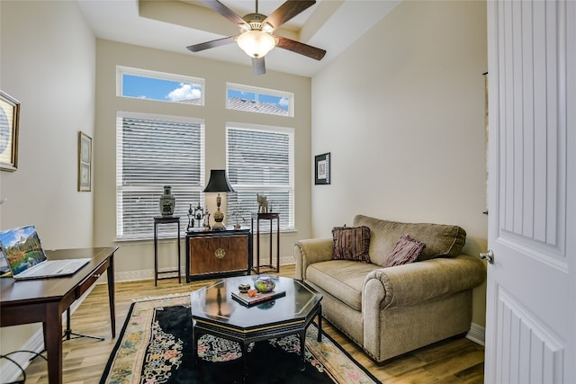 living room featuring baseboards, a ceiling fan, and wood finished floors