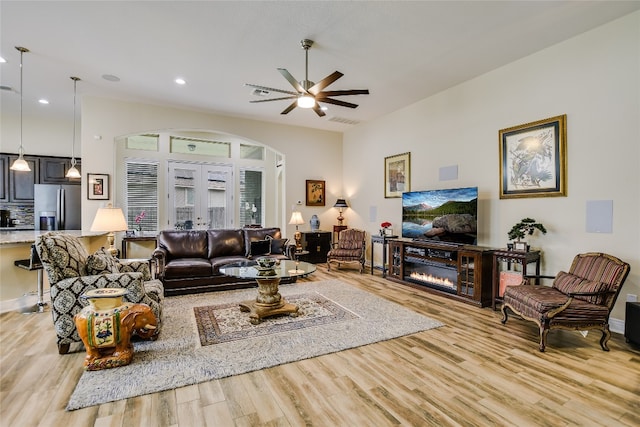 living area featuring visible vents, ceiling fan, light wood-type flooring, recessed lighting, and arched walkways