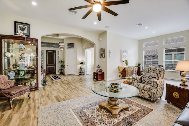 living area featuring arched walkways, a ceiling fan, recessed lighting, wood finished floors, and visible vents