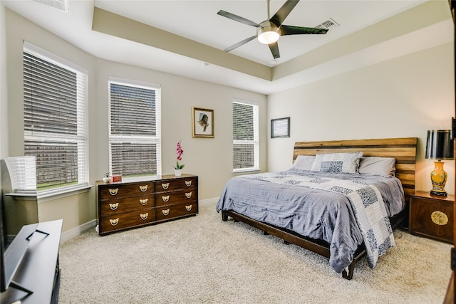 bedroom with baseboards, multiple windows, a tray ceiling, and carpet