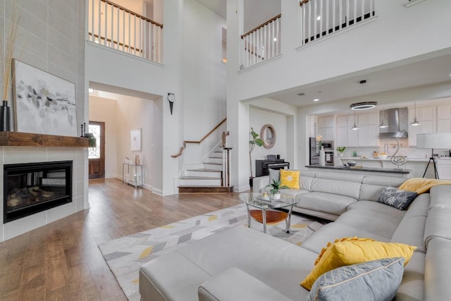 3908 Logan Ridge Dr, Cedar Park, TX 78613 - living area featuring wood finished floors, stairway, a tiled fireplace, and a towering ceiling