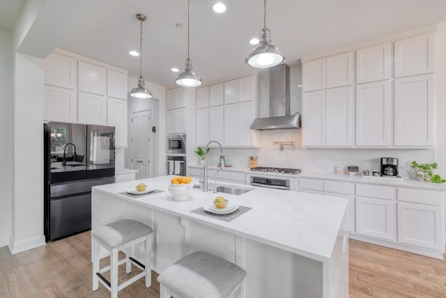 3908 Logan Ridge Dr, Cedar Park, TX 78613 - kitchen with appliances with stainless steel finishes, wall chimney exhaust hood, a sink, white cabinets, and light wood-type flooring