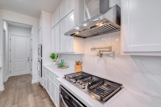 3908 Logan Ridge Dr, Cedar Park, TX 78613 - kitchen with wall chimney range hood, stainless steel appliances, white cabinetry, tasteful backsplash, and light wood-style flooring