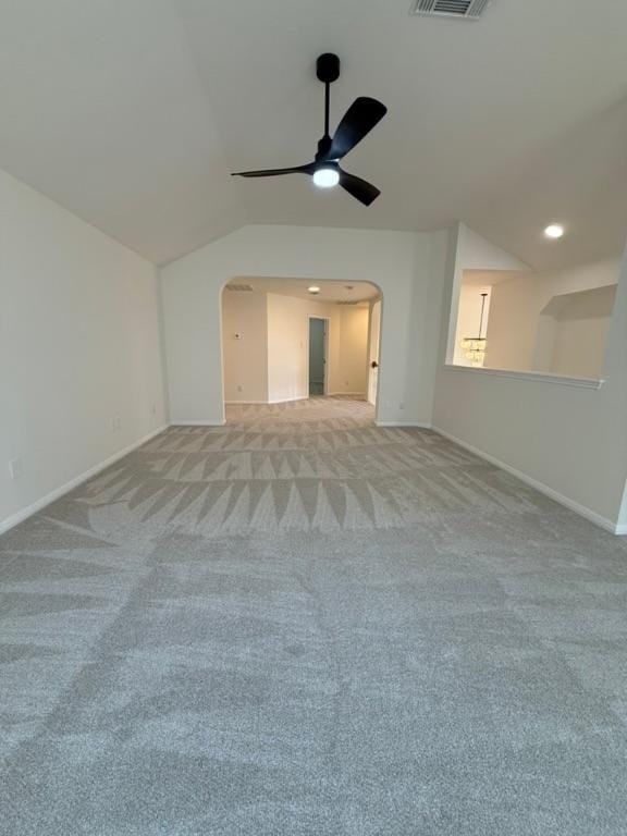 spare room featuring lofted ceiling, baseboards, light colored carpet, arched walkways, and a ceiling fan