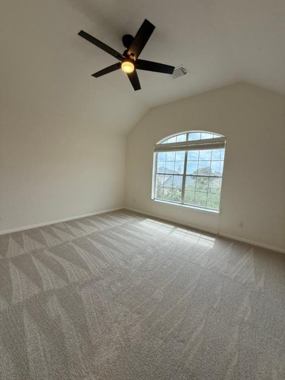 carpeted empty room with baseboards, ceiling fan, lofted ceiling, and visible vents