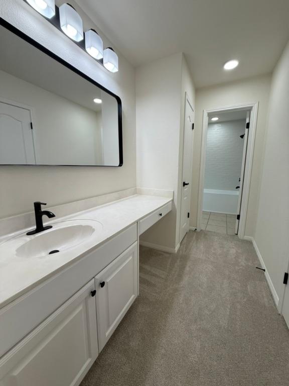 bathroom with carpet flooring, recessed lighting, baseboards, and vanity