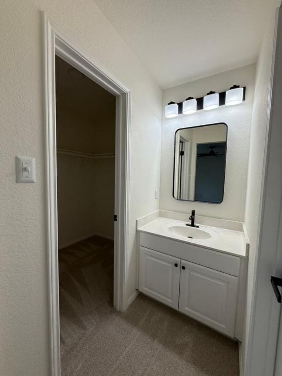 bathroom with vanity and a walk in closet