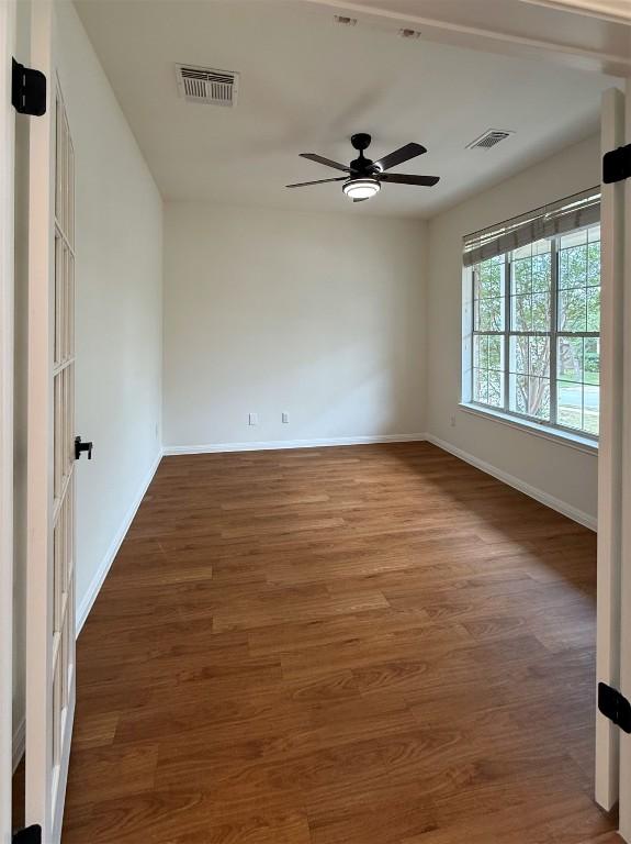 unfurnished room featuring visible vents, baseboards, and wood finished floors