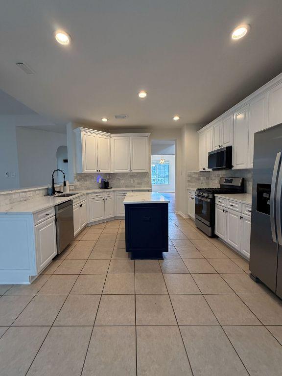 kitchen with a sink, appliances with stainless steel finishes, decorative backsplash, and white cabinetry
