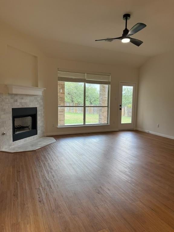 unfurnished living room with a ceiling fan, a fireplace with flush hearth, plenty of natural light, and wood finished floors