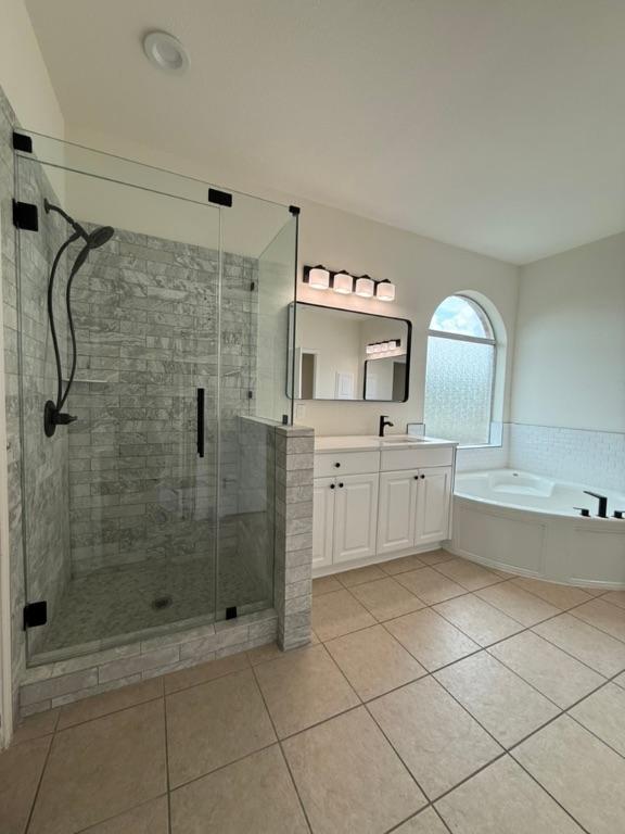 bathroom featuring tile patterned flooring, a stall shower, a garden tub, and vanity