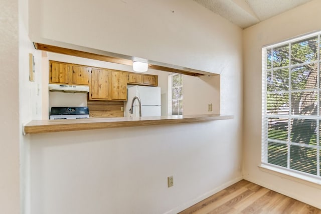 11948 Sunhillow Bnd Unit A & B, Austin, TX 78758 - kitchen featuring under cabinet range hood, freestanding refrigerator, stove, light wood-style floors, and a peninsula
