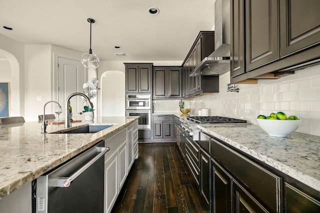 308 Cuore Bianco Cv, Lakeway, TX 78738 - kitchen with arched walkways, appliances with stainless steel finishes, a sink, wall chimney exhaust hood, and dark wood finished floors