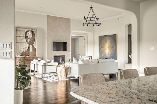 308 Cuore Bianco Cv, Lakeway, TX 78738 - dining room featuring a tiled fireplace, crown molding, arched walkways, a chandelier, and dark wood-style floors
