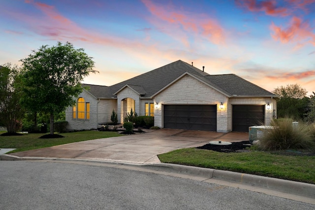 ranch-style home with a garage, a front lawn, stone siding, a shingled roof, and concrete driveway