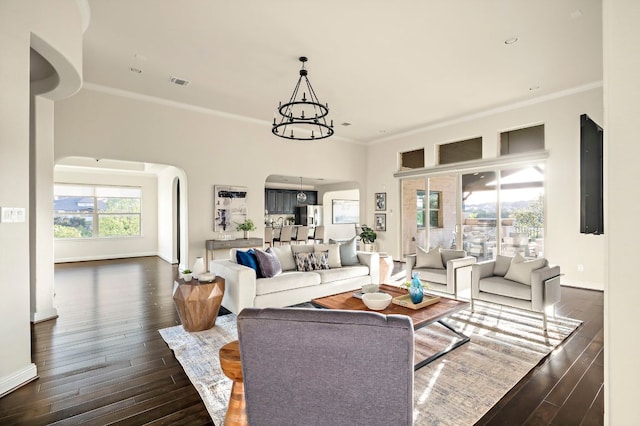 living area featuring crown molding, arched walkways, visible vents, and dark wood-type flooring