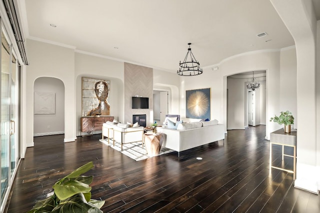 living area with an inviting chandelier, arched walkways, a fireplace, and dark wood-style floors