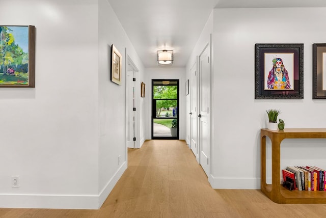 hallway featuring baseboards and light wood-style floors