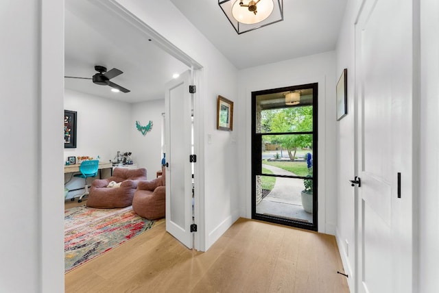 foyer entrance with a ceiling fan, baseboards, and wood finished floors