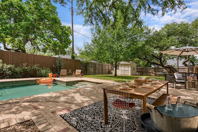 view of swimming pool with a patio, a fenced backyard, an outbuilding, a jacuzzi, and a storage shed